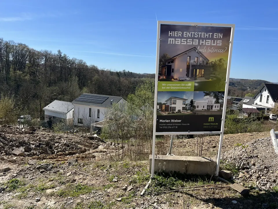 Bauschild „Hier entsteht ein massa haus – auch Interesse?“ auf einem erschlossenen Bauplatz